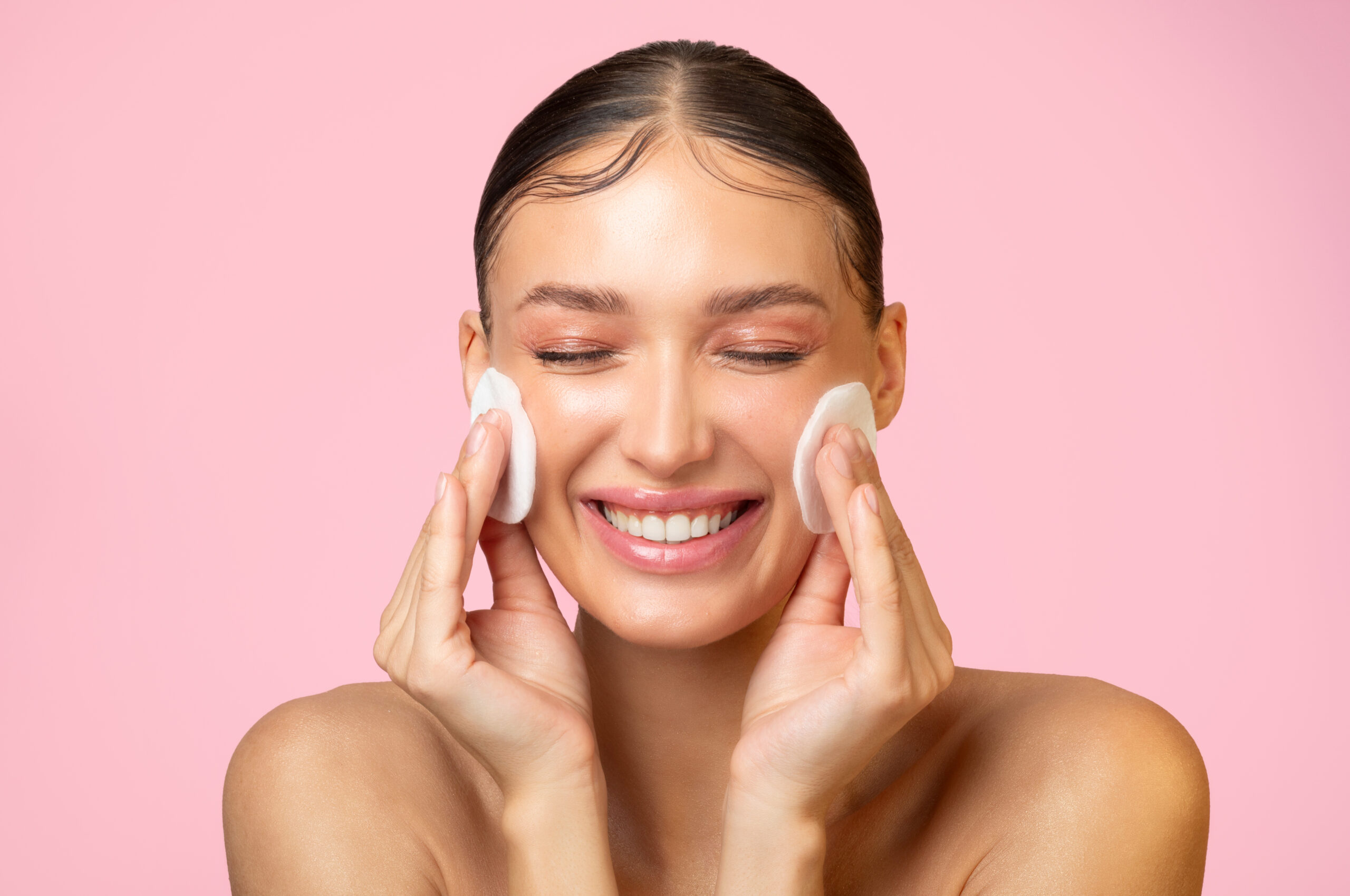 daily skincare excited young lady cleaning face with cotton pads smiling doing skin care routine.jpg